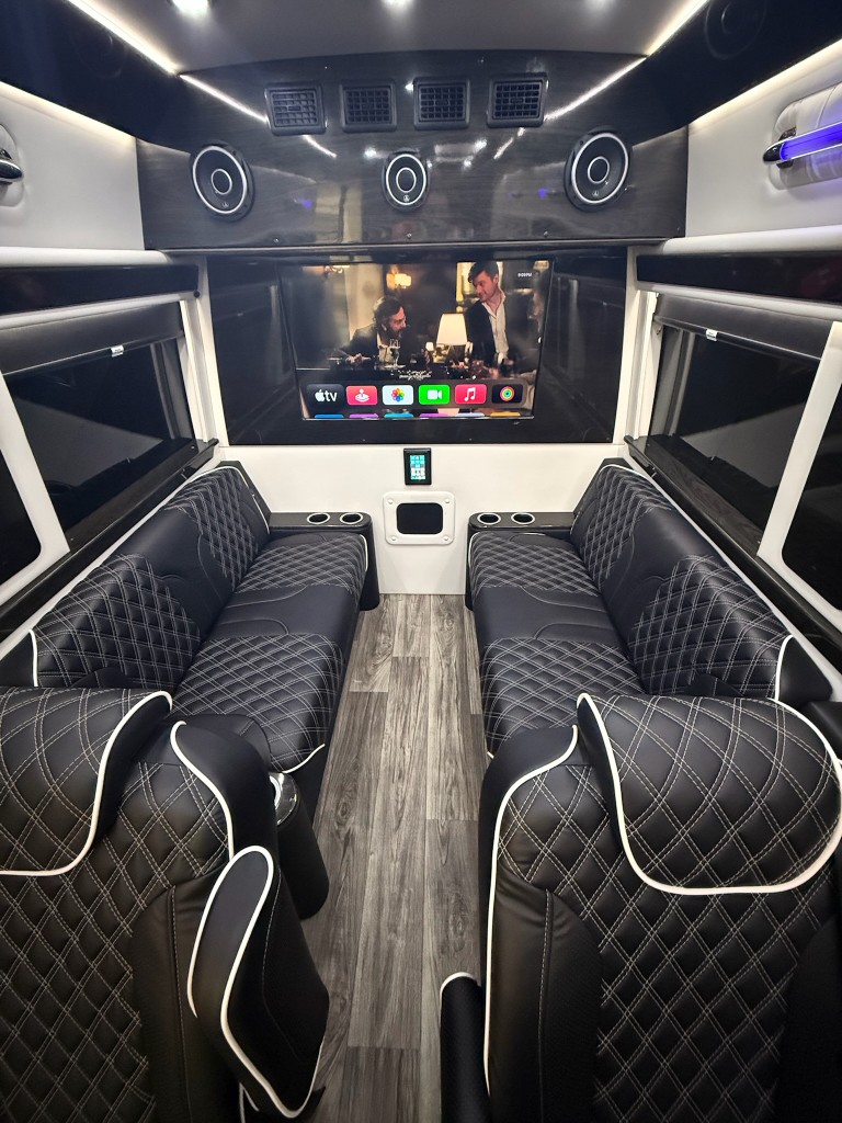 Luxury shuttle interior with leather seating, entertainment system, and ambient lighting, Miami event transportation comfort and safety