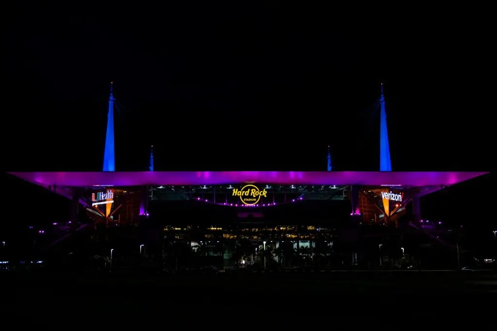 Hard Rock Stadium lit purple and blue at night in Miami Gardens