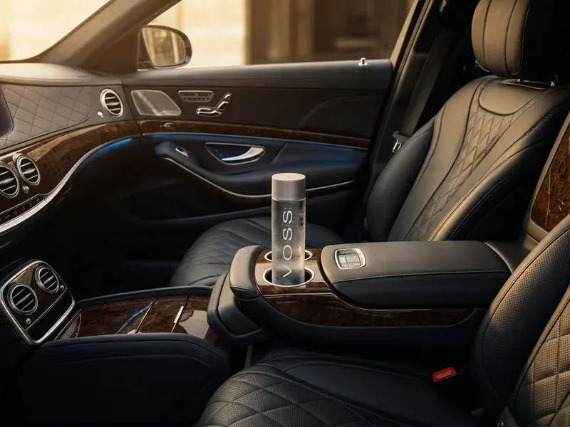 White Mercedes-Benz Sprinter van parked outside a luxury Miami hotel with its door open, showing leather captain chairs and ambient interior lighting