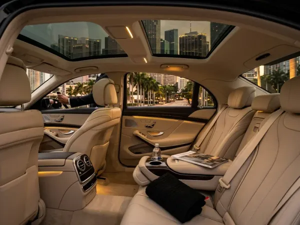 Couple in formal attire sharing champagne in the rear cabin of a luxury sedan as it crosses the lit Rickenbacker Causeway toward Miami for a romantic anniversary dinner