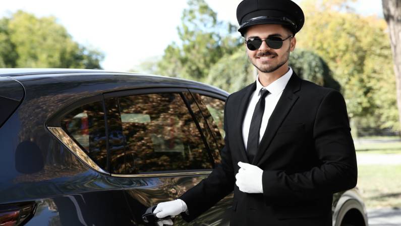 Young handsome driver opening luxury car door.