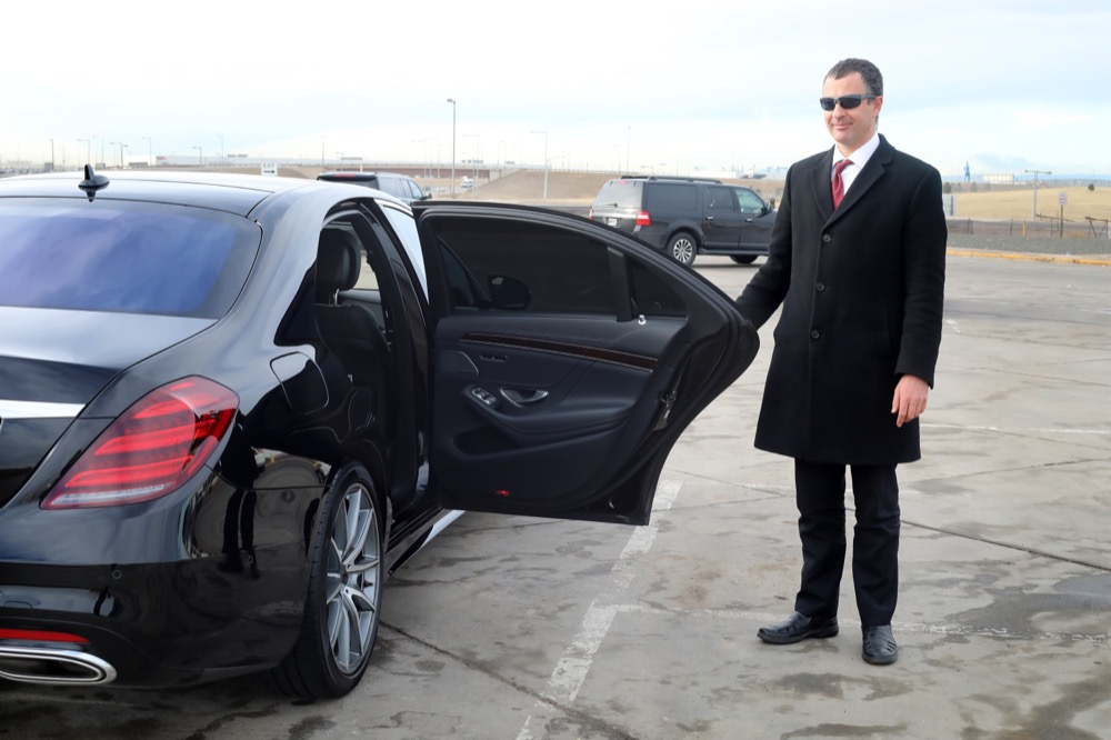 Chauffeur holds a rear passenger door open