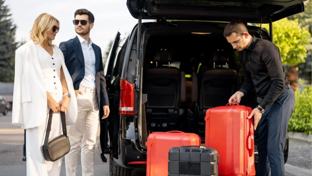 Chauffeur loads luggage into a black van while a stylish couple waits, highlighting luxury airport car service in Miami.