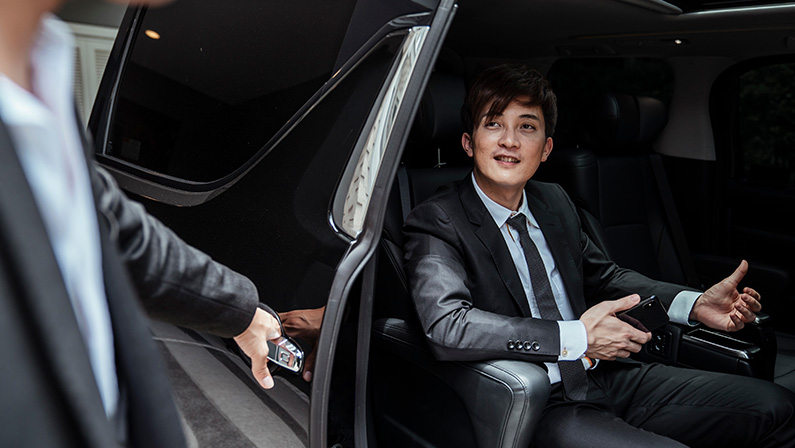 chauffeur opeing the car door for his boss to come out.