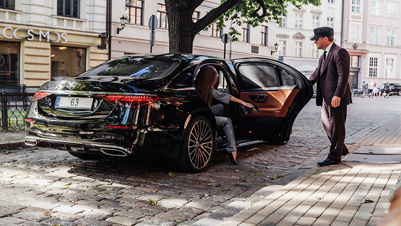 Riga, Latvia 21 July 2021 Limousine transfer chauffeur with chauffeur hat, stands by luxury car and open door for client. Mercedes Benz S500 AMG S class w223 brand new model