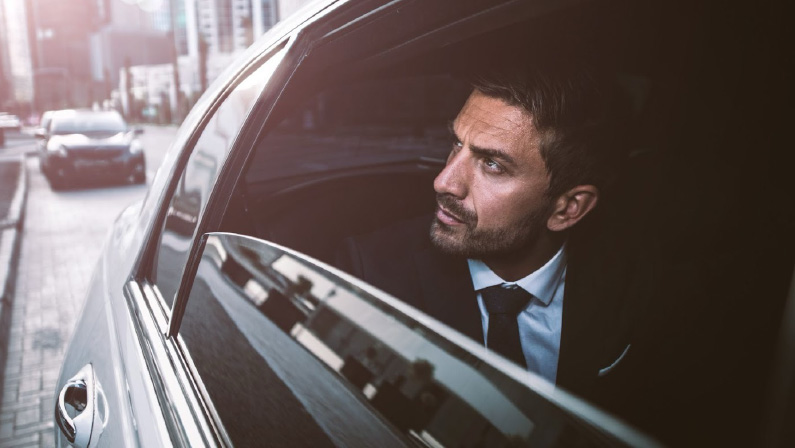 chauffeur opeing the car door for his boss to come out.