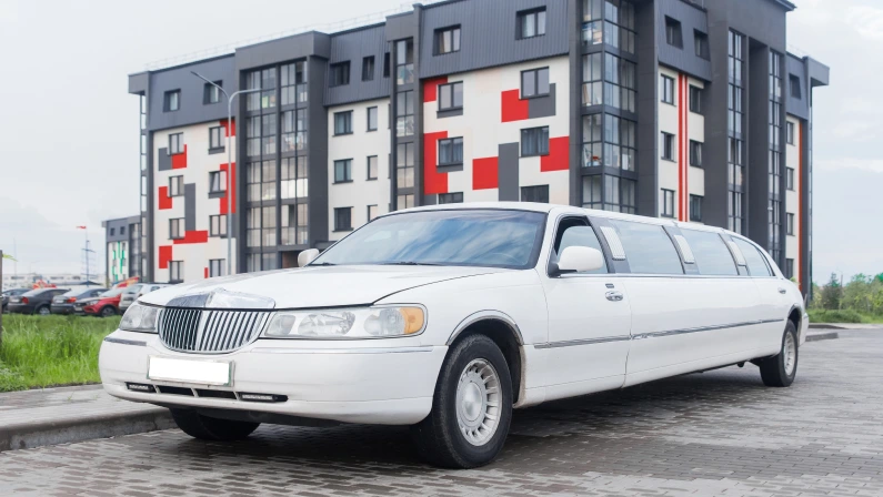 White limousine luxury long car for celebrations and celebrations against the backdrop of a modern city building.