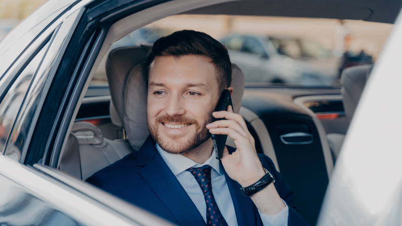 Happy company manager listening to his employee on topic of financial gain, hearing about high amount of profit possibilities, ready to go and make money, riding in back of luxury car