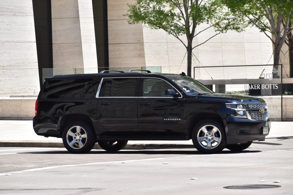  A portrait of a black Chevrolet Suburban SUV driving in the downtown