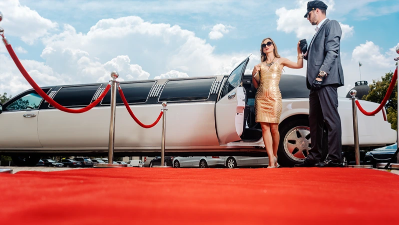 Driver helping VIP woman or star out of limo on red carpet to a reception